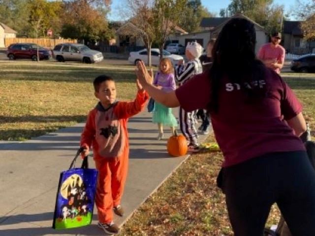 Child getting a "high five" from a staff member at El Centro's Trunk n Treat 2022
